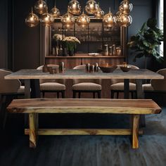 a dining room table and chairs with lights hanging from the ceiling above it, in front of a bar