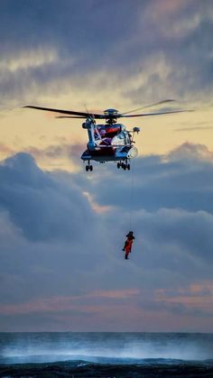 a man is being pulled by a helicopter over the ocean