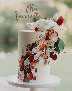 a wedding cake decorated with flowers and leaves