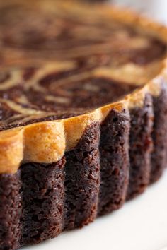 a chocolate cake on a white plate with icing in the middle and swirl designs on top