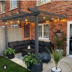 an outdoor living area with couches and potted plants in front of a brick building