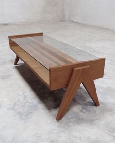 a coffee table with a glass top and wooden legs on concrete floor in an empty room