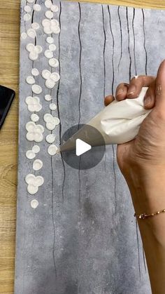 a woman is painting on a piece of paper with white circles and black lines in the background