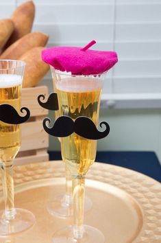 two champagne flutes with fake mustaches on them sitting on a table next to bread