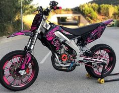 a pink and black dirt bike parked in a parking lot