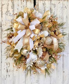 a wreath with gold and white ornaments hanging on a door