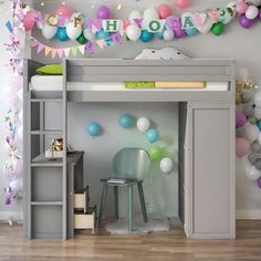 there is a loft bed with a desk underneath it and balloons all around the room