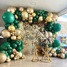 a room filled with lots of green and gold balloons