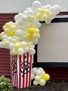 a popcorn box filled with white and yellow balloons