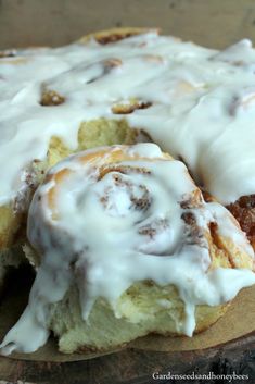 a cinnamon roll with icing sitting on top of a wooden plate