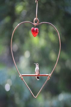 Hummingbird perched on a copper heart shaped swing that has a red hear shaped bead to attract them Ladybug House, Bird Feeder Poles, Handmade Birdhouses, Attract Hummingbirds, Wire Heart, Hanging Bird Feeders, Copper Heart