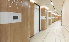 a long hallway with wooden walls and white doors on both sides is lit by recessed lights