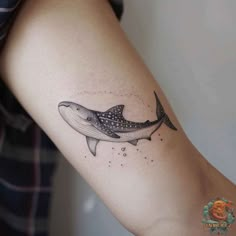 a woman's arm with a tattoo of a whale and dots on the side