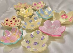 small ceramic bowls with flowers painted on them sitting on a white cloth covered tablecloth