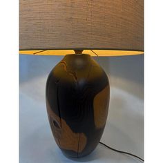 a table lamp with a brown and black design on the base, next to a beige shade