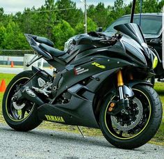 the motorcycle is parked on the side of the road next to an orange cone with trees in the background