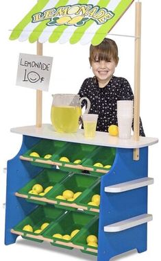 a young boy standing behind a lemonade stand