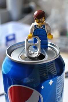 a lego man is sitting on top of a can of soda with the lid open