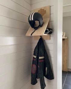 a motorcycle helmet and jacket hang on a shelf next to a pair of gloves hanging from the wall