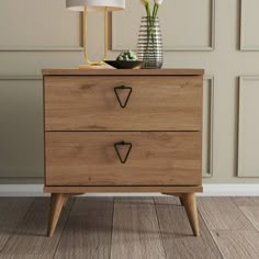 a wooden dresser with two drawers and a lamp next to it on top of a hard wood floor