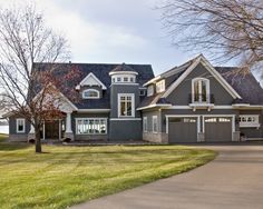 a large gray house with lots of windows and two car garages on the driveway