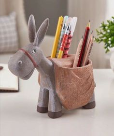 a donkey shaped pencil holder on a table with pens and pencils in it's pouch