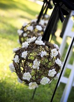 white flowers are hanging from the back of an outdoor wedding ceremony chair with black ribbon