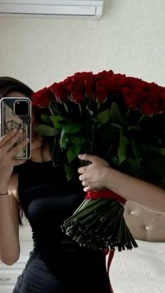 a woman taking a selfie while holding a bouquet of roses