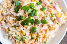 a white bowl filled with corn salad on top of a wooden table