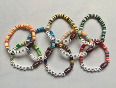 six bracelets with words written in different colors and sizes are shown on a white surface