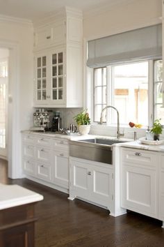 a large kitchen with white cabinets and wood floors