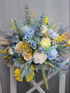 a bouquet of flowers sitting on top of a white chair with blue and yellow flowers