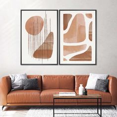 two abstract paintings hang on the wall above a leather couch in a modern living room