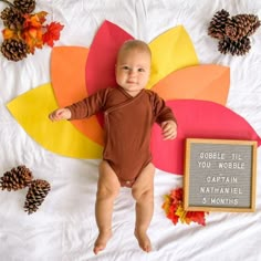 a baby laying on top of a bed next to a sign