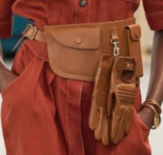 a woman in an orange jumpsuit with brown gloves on her belt and one hand holding a cell phone