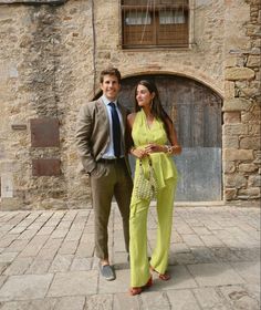 a man and woman standing next to each other in front of an old brick building