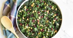 a white bowl filled with spinach and nuts on top of a blue checkered towel