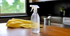 a bottle of cleaner sitting on top of a wooden table next to a yellow towel