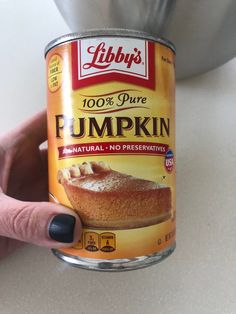 a can of pumpkin pudding being held up by a woman's hand on a counter