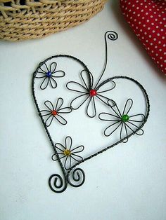 a wire heart with flowers on it sitting next to a basket