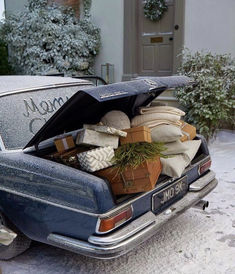 an old car is loaded with presents and wrapped in wrapping on the snow covered driveway