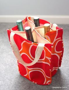 an orange and white bag with some pens in it