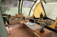 a laptop computer sitting on top of a wooden table in a room filled with tents