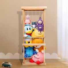 several stuffed animals in a wooden cage on the floor next to a toy car and window