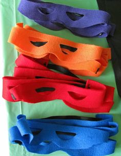 five different colored masks sitting on top of each other in front of a green sheet