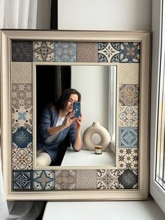 a woman taking a selfie with her cell phone in front of a decorative mirror