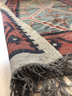 an old rug is laying on the floor with some tassels hanging from it