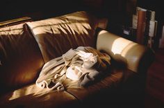 an unmade bed is sitting on the couch in the sun light, with sheets draped over it