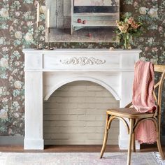 a chair sitting in front of a fireplace with a painting on the wall behind it