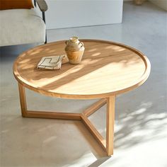 a wooden table with a vase on it in front of a white couch and chair